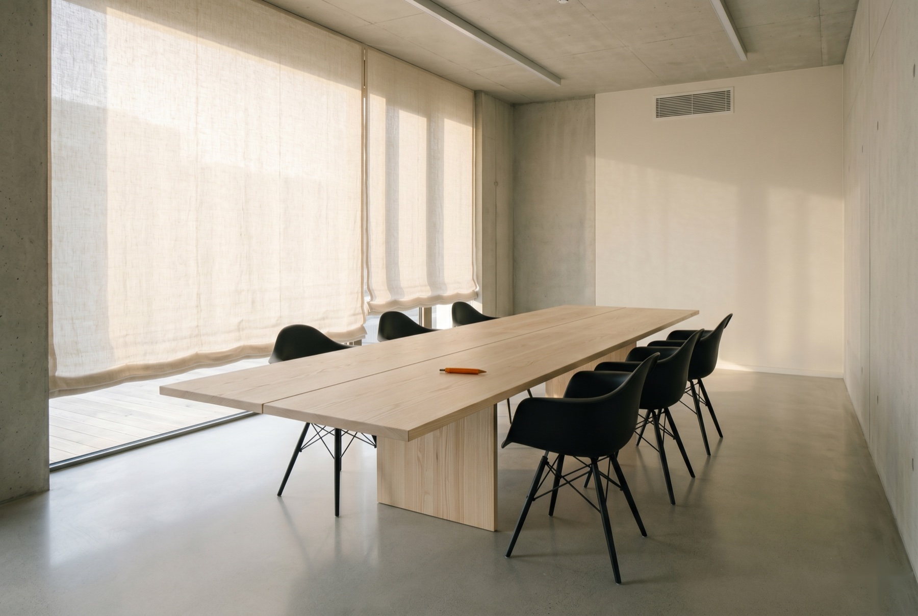 Quiet modernist meeting room with ash-wood table, matte-black chairs, and warm linen-filtered light — Krasper briefing space